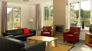 A modern living room with a sofa, armchairs, a coffee table, a fireplace, and a television. - House With Bubble Bath, at 20 km. From Assen (Westerbork)