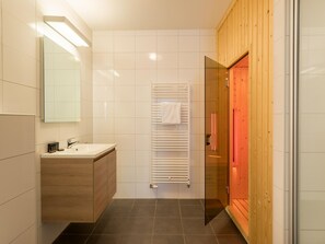 Een moderne badkamer met een houten wastafelmeubel, een douchecabine met glazen wanden en een witte handdoekhouder.