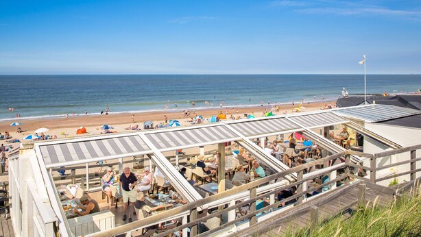 A beachside restaurant with outdoor seating overlooking the ocean.