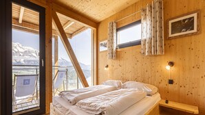 A wooden cabin bedroom with a bed, a window, and a view of mountains. - Chalet With Panoramic Sauna (Schladming)