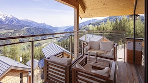A wooden balcony with a sofa and chairs, offering a view of a mountainous landscape. - Chalet With Panoramic Sauna (Schladming)