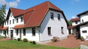 A two-story building with a red-tiled roof, white walls, and a brick pathway leading to the entrance. - Landhaus mit Schwimmbad in Dargun (Dargun)