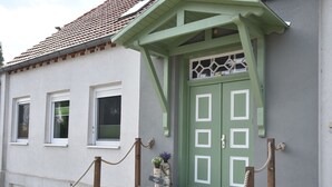 Ein Gebäude mit einer grünen Tür, weißen Fensterrahmen und Steinstufen, die zum Eingang führen.