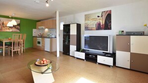 Eine moderne Küche mit Essbereich, einem Glastisch und einem Flachbildfernseher.