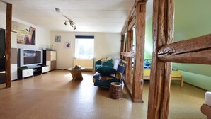 Ein Wohnzimmer mit Fernseher, Sofa und Fenster.