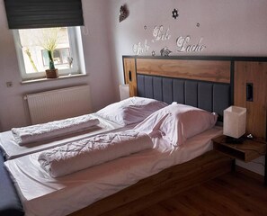 A double bed with white linens in a room with a wooden headboard and a small bedside table with a lamp. - Enticing Apartment in Stormbruch near Ski Area (Diemelsee)