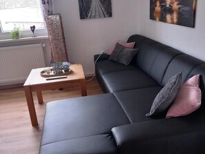A modern living room with a black sofa, a wooden coffee table, and a radiator. - Enticing Apartment in Stormbruch near Ski Area (Diemelsee)