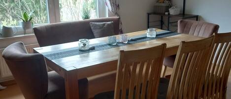 A dining area with a wooden table, chairs, and a view of trees through the window.