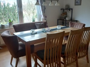 A dining area with a wooden table, chairs, and a view of trees through the window. - Enticing Apartment in Stormbruch near Ski Area (Diemelsee)