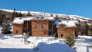 A large wooden chalet with multiple levels, a ski lift, and a snowy mountain backdrop. - Chalet in France Near Ski Slopes (Le Dévoluy)