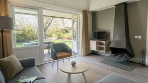Ein modernes Wohnzimmer mit einer Couch, einem Couchtisch, einem Fernseher auf einem Schrank und einem Kamin.