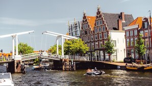 Een gracht met boten, een brug en historische gebouwen met rode bakstenen gevels.