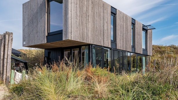 Een modern houten herenhuis met twee verdiepingen, grote ramen en een plat dak.