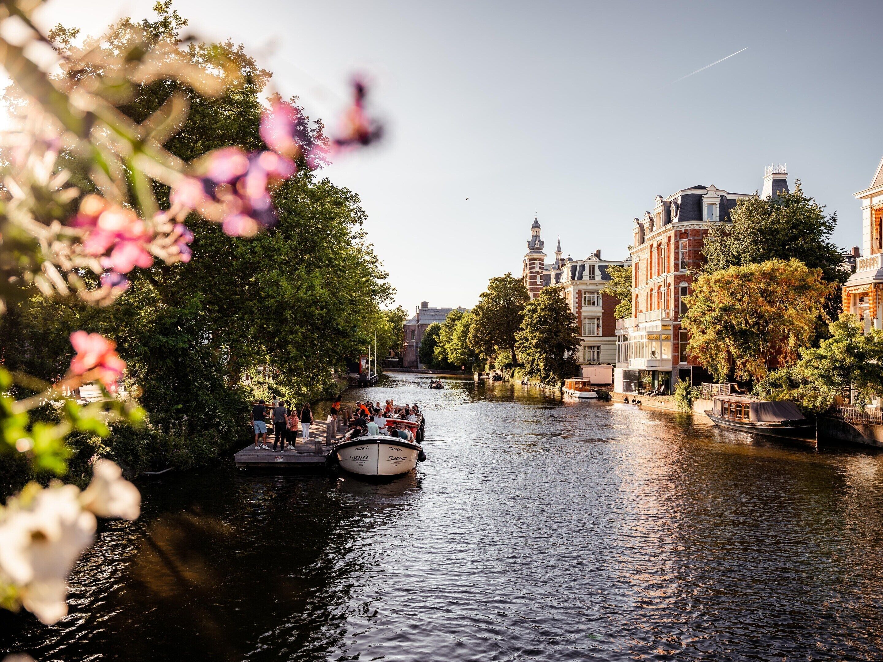 A canal with boats, surrounded by historic buildings and trees.