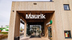 Un edificio moderno con facciata in legno e un cartello con su scritto "Maurik".