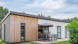 A modern house with a wooden exterior, a patio with a table and chairs, and a large umbrella. - Cozy Chalet w/ Shared Pool (Borger)