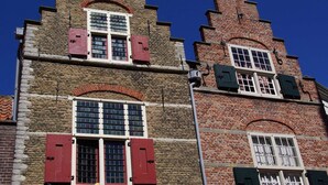 A historic building with a steeply pitched roof, red window shutters, and a brick facade. - Bungalow Near Veerse Meer & Beach (Kamperland)