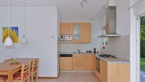 A modern kitchen with wooden cabinets, a built-in microwave, and a gas stove. - Bungalow Near Veerse Meer & Beach (Kamperland)