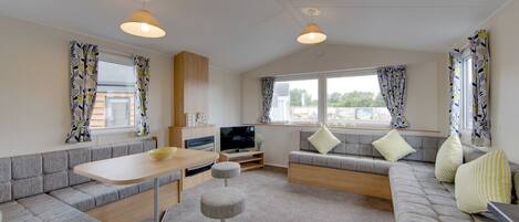 A modern living room with a sofa, ottoman, and a dining table.