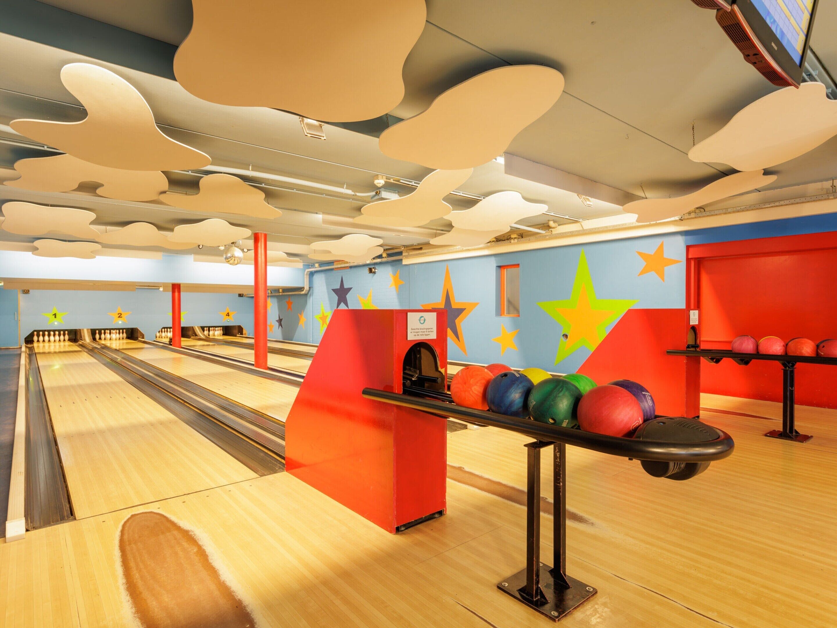 A bowling alley with lanes, pins, and a bowling ball rack.