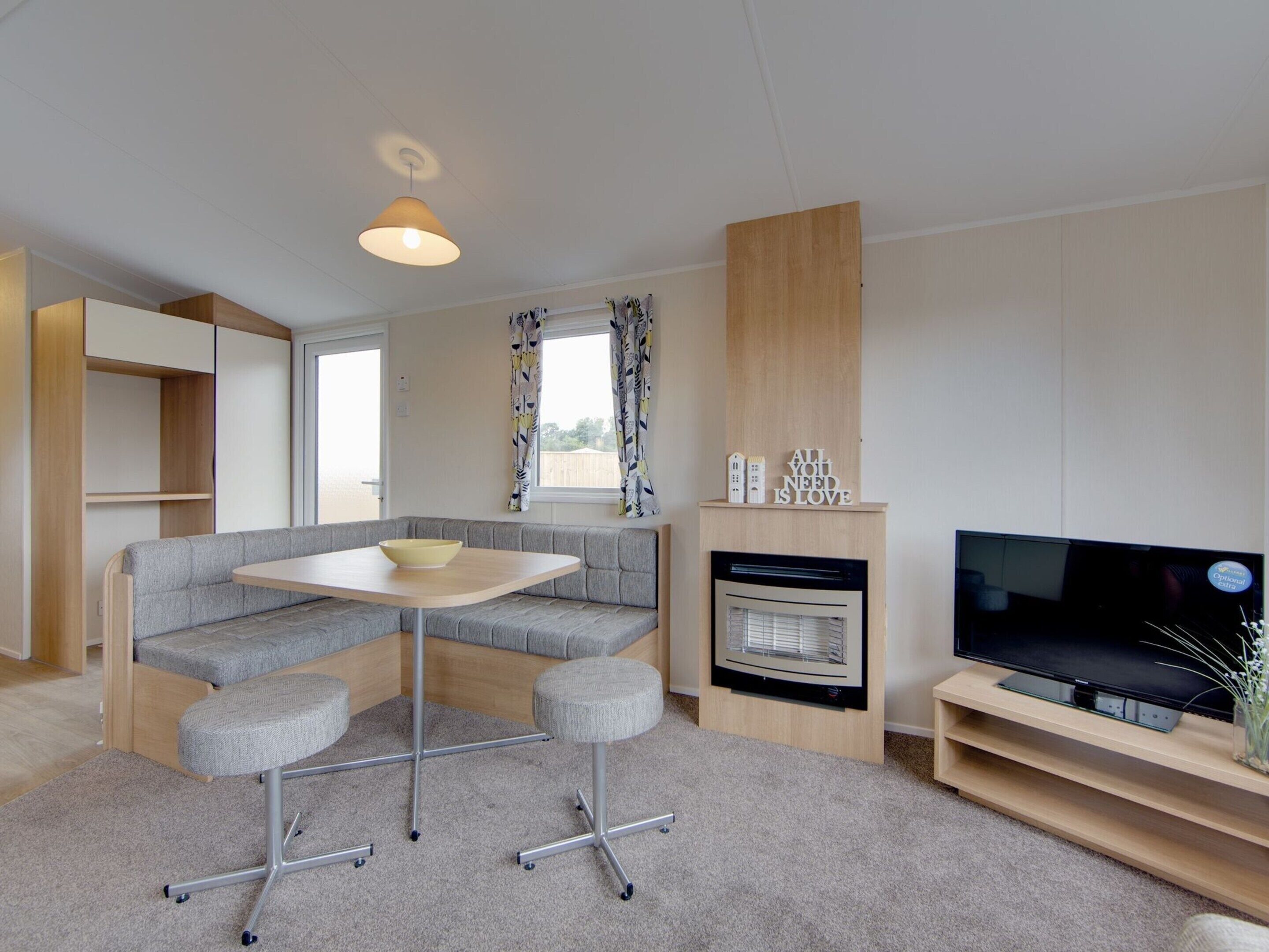 Un espace de vie compact comprenant un canapé, une petite table, un téléviseur et une cheminée.