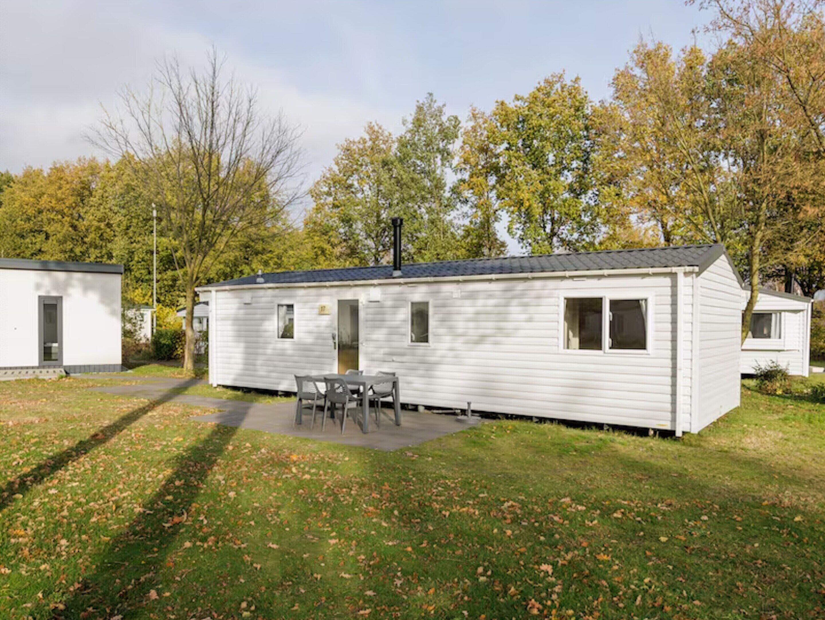 Une maison mobile de plain-pied dotée d’un patio, d’une table et de chaises.