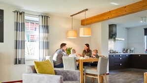 Une famille est réunie autour d’une table dans une cuisine moderne, avec des chaises et une machine à café.