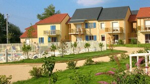 A row of yellow buildings with balconies, a fenced pool area, and a well-maintained lawn. - Holiday Home in Montignac Near Lascaux II (Montignac)