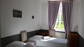 A room with two beds, a window with curtains, a framed picture on the wall, and a small table with a lamp. - Castle in Asnieres With Tennis & Forest Views (Asnieres)
