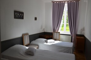 A room with two beds, a window with curtains, a framed picture on the wall, and a small table with a lamp. - Castle in Asnieres With Tennis & Forest Views (Asnieres)