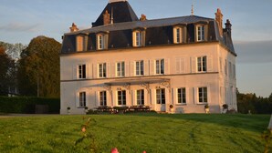 A large, two-story building with a symmetrical facade, multiple windows with shutters, and a prominent central tower. - Castle in Asnieres With Tennis & Forest Views (Asnieres)