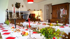A dining room with multiple tables set for a meal, featuring white tablecloths, red napkins, and candle holders. - Castle in Asnieres With Tennis & Forest Views (Asnieres)