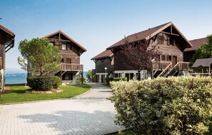 A row of wooden cabins with balconies, a paved pathway, and a view of the water. - Apartment in Evian Near Lake Geneva (Evian-les-Bains)