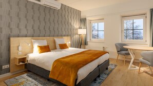 Ein modernes Hotelzimmer mit einem großen Bett, Nachttischen, einem Schreibtisch und zwei Stühlen.
