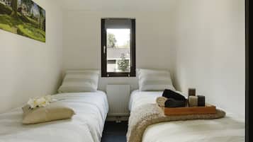 A small, clean room with two beds, a window, and a radiator.