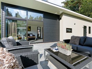 A modern outdoor living area with a sofa, chairs, and a coffee table. - Wellness Forest Retreat (Markelo)