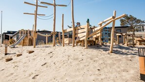 A wooden playground with slides and climbing structures on a sandy beach. - Cozy Chalet With Dishwasher in Noordwijk, Near the Sea (Noordwijk)