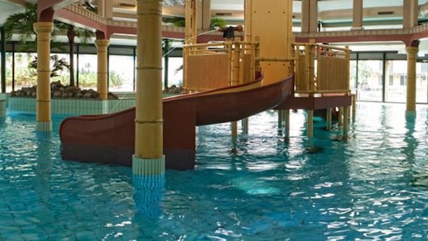 An indoor swimming pool with a wooden boat slide, multiple levels, and a central water feature. - Modern Bungalow With Washer (Arcen)