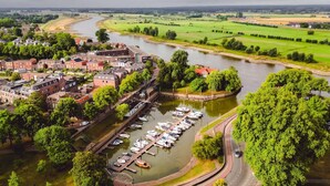 A riverside town with a marina, buildings, and green fields. - Private Chalet in the Woods (Epe)