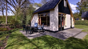 Une petite maison de plain-pied, dotée d’un toit en pente et de grandes fenêtres.