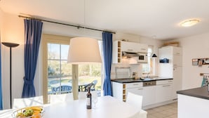 A modern kitchen with white cabinets, a dining area with a white table, and a view of the outdoors through large windows. - Comfortable Villa With Wifi, Near the Sea in Cosy Domburg (Domburg)