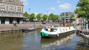 A canal with boats, a historic building with a clock tower, and a tree-lined promenade. - Unique Holiday Home in Bergen aan Zee With Terrace (Bergen aan Zee)