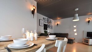 A dining area with a wooden table set for four, white chairs, and candles. - Unique Holiday Home in Bergen aan Zee With Terrace (Bergen aan Zee)
