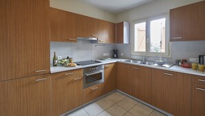 A modern kitchen with wooden cabinets, stainless steel appliances, and a window providing natural light. - Villa in France With Private Garden (Lanzac)