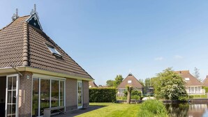 A house with a sloped roof, a brick exterior, and a glass door. - Canal-side Bungalow Stay (Earnewald)
