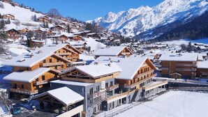 A snow-covered mountain resort with wooden buildings, ski slopes, and a clear view of the mountains. - Chalet in La Clusaz With Spa & Ski Access (La Clusaz)