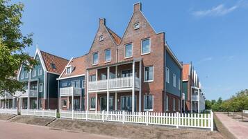 A row of modern brick townhouses with white railings and multiple windows.