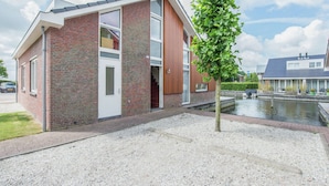 A modern two-story house with a brick facade, large windows, and a small tree in the foreground. - Apartment in Waterpark With Private Jetty (Uitgeest)