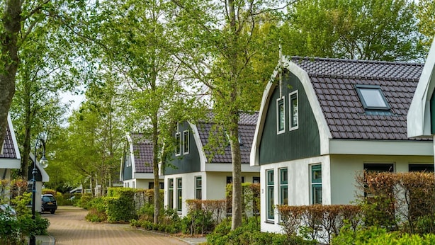 A row of traditional houses with sloped roofs and dormer windows, surrounded by lush greenery and a paved driveway. - Detached Holiday Home in Schoorl With Garden (Schoorl)