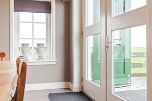 Una habitación con una mesa de comedor, un ventanal con vistas y una puerta que da al exterior.